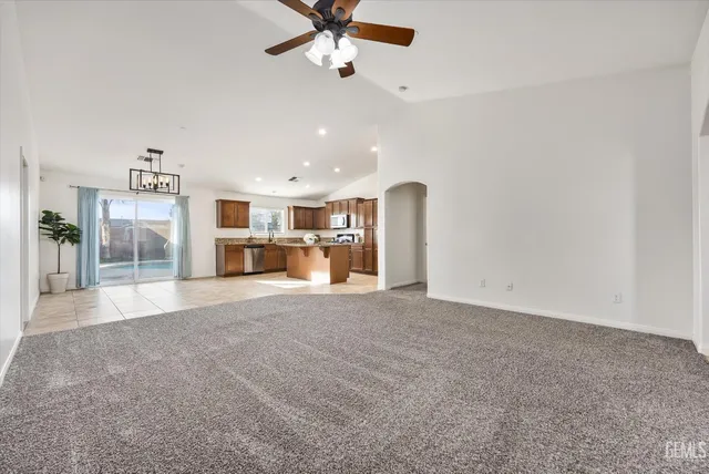 a large kitchen with stainless steel appliances kitchen island granite countertop a refrigerator and a sink