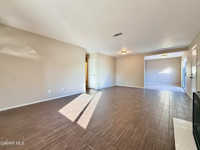 a view of an empty room with wooden floor and door