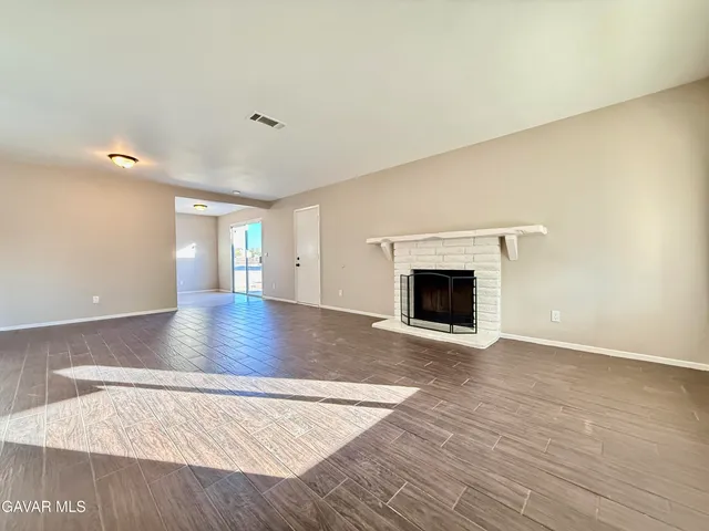 a view of an empty room with a fireplace and a window