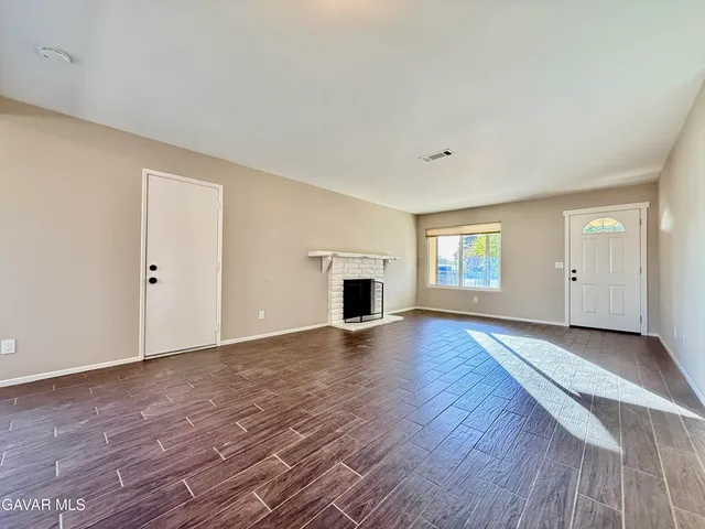a view of empty room with wooden floor and fireplace