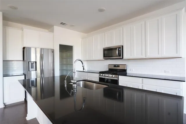 a kitchen with stainless steel appliances granite countertop a refrigerator a stove a sink a counter space and cabinets