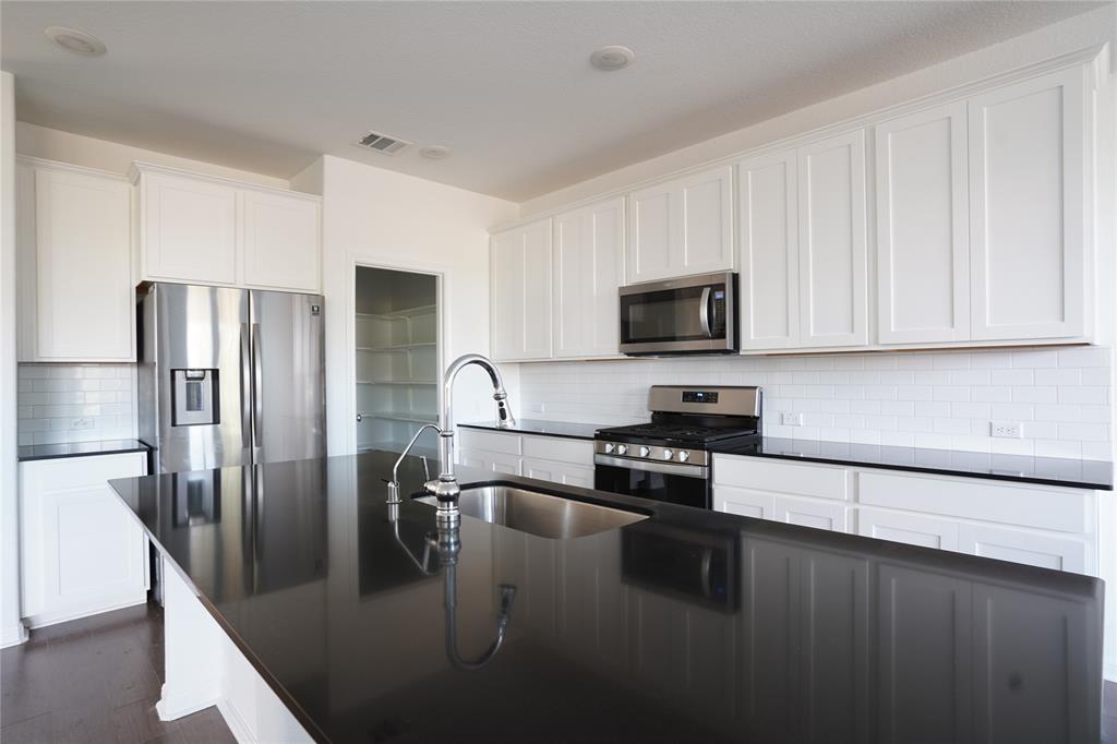 a kitchen with stainless steel appliances granite countertop a refrigerator a stove a sink a counter space and cabinets