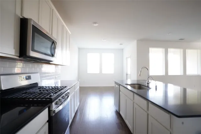 a kitchen with stainless steel appliances granite countertop a stove a sink and a microwave