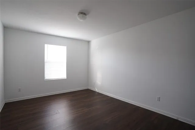 an empty room with wooden floor and window