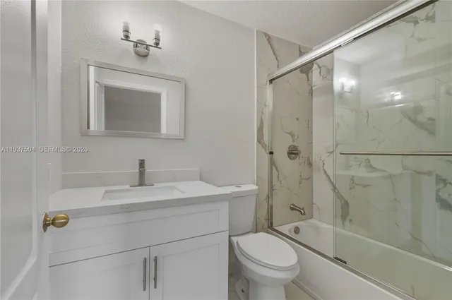 a bathroom with a toilet sink vanity shower and mirror