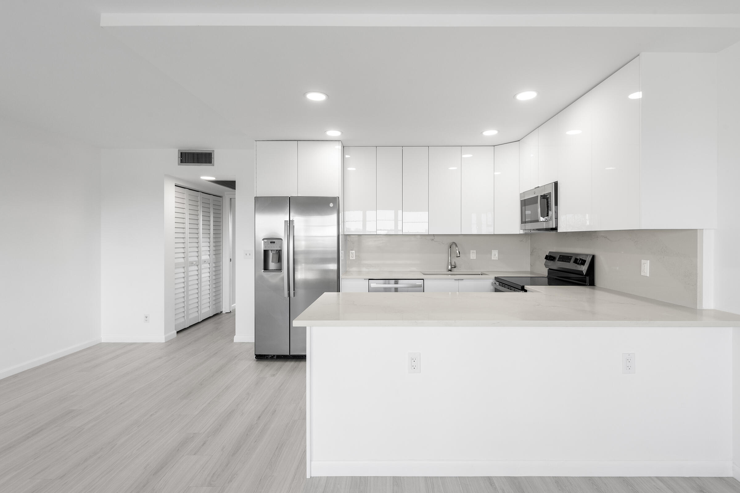 4043 Rexford Drive, Unit 4043 Boca Raton, FL 33434 - Photo 7 of 27 a large white kitchen with a refrigerator a sink dishwasher and a stove with wooden floor
