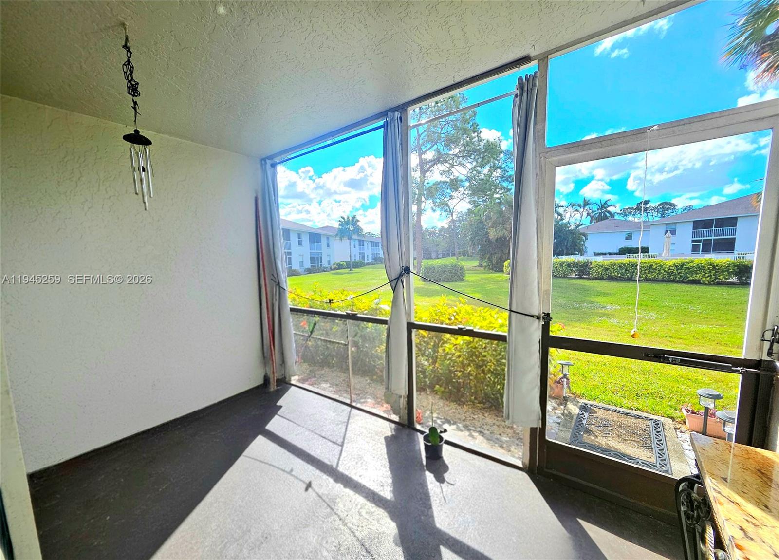 1448 Churchill Circle, Unit 103 Naples, FL 34116 - Photo 26 of 37 a view of an empty room with wooden floor and a floor to ceiling window