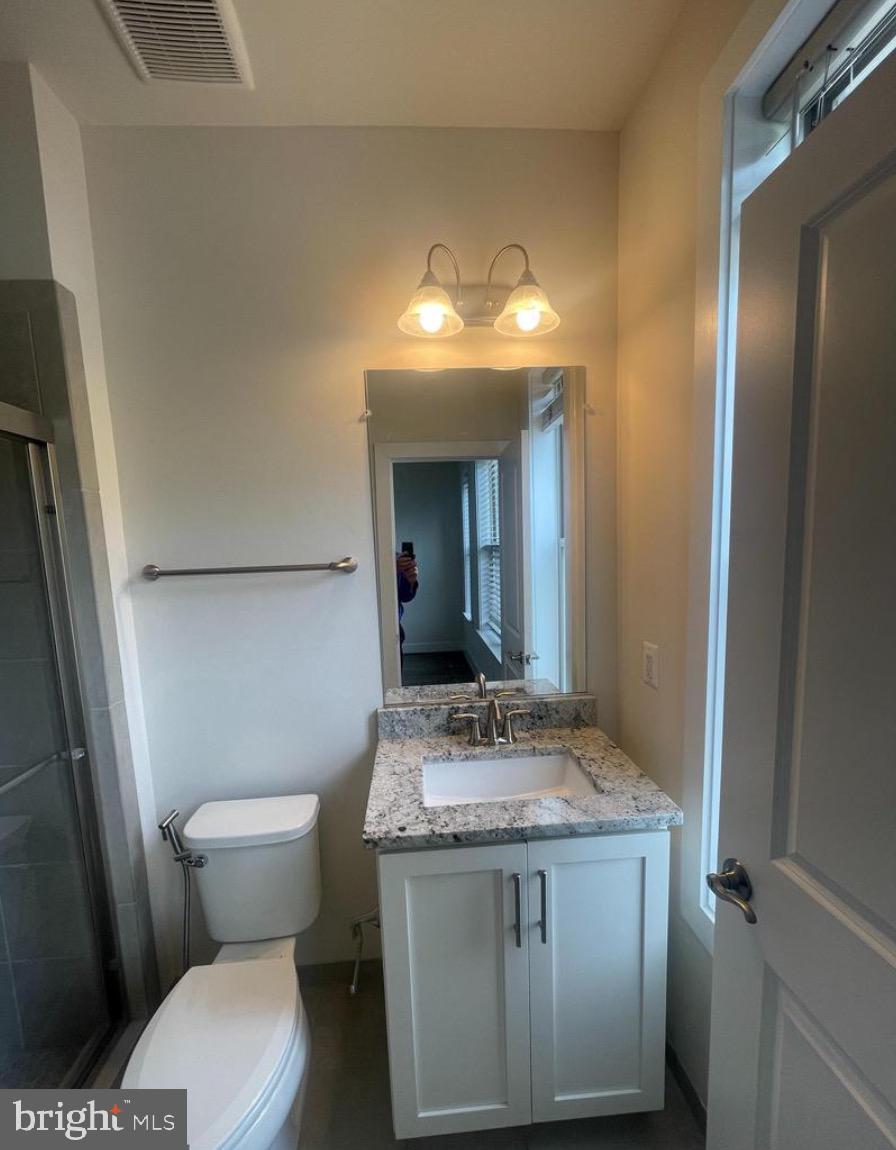 2228 South Glebe Road Arlington, VA 22204 - Photo 23 of 34 a bathroom with a granite countertop toilet a sink and a mirror