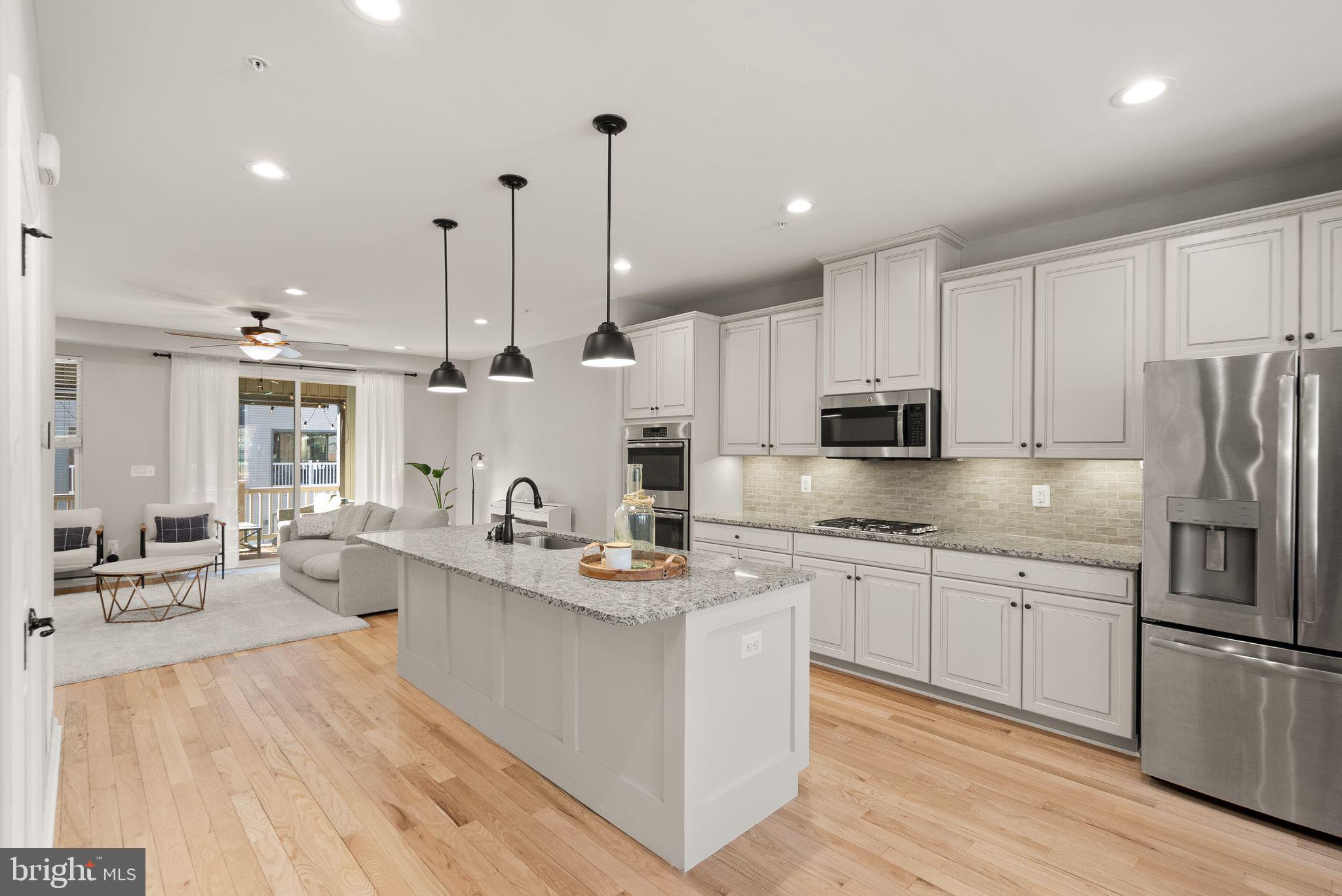 43405 Charitable Street Ashburn, VA 20148 - Photo 11 of 44 a large kitchen with stainless steel appliances kitchen island granite countertop a stove a sink a refrigerator and white cabinets with wooden floor