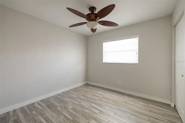 an empty room with wooden floor and ceiling fan