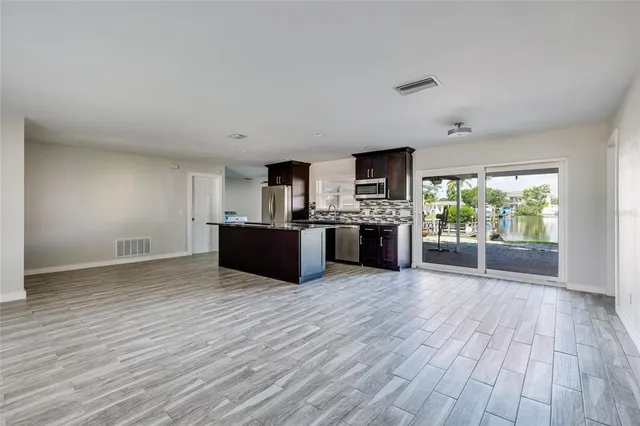 a view of kitchen with kitchen island wooden floor and stainless steel appliances