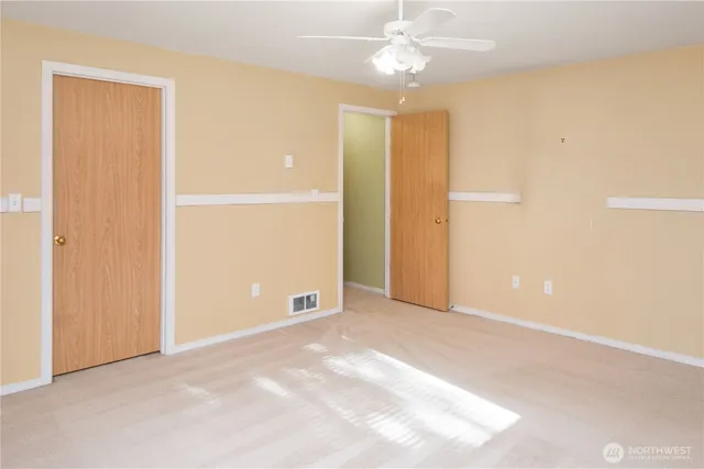 an empty room with closet and a ceiling fan