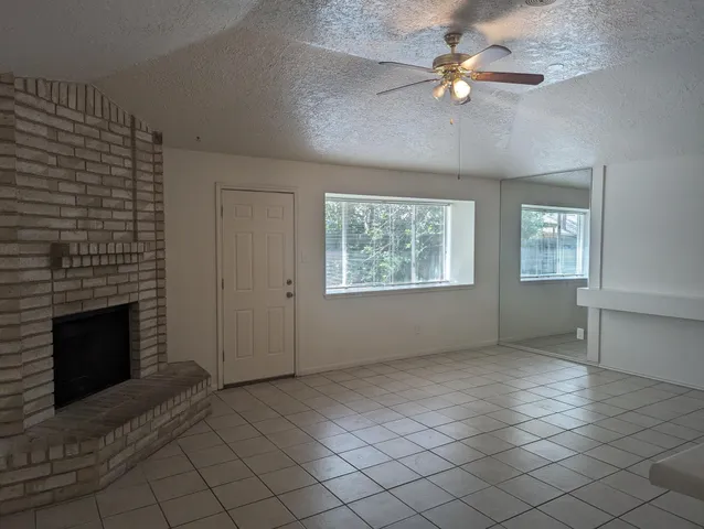 an empty room with windows and fireplace