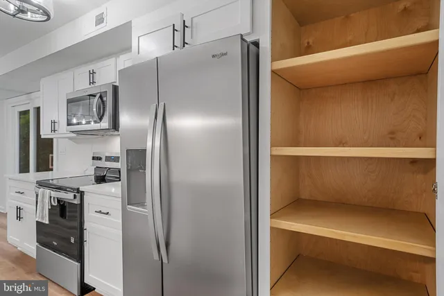 a kitchen with a refrigerator and white cabinets