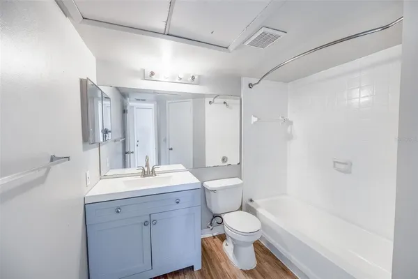 a bathroom with a toilet a sink a mirror a bathtub and vanity