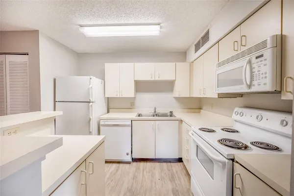 a kitchen with a sink a stove a refrigerator and white cabinets