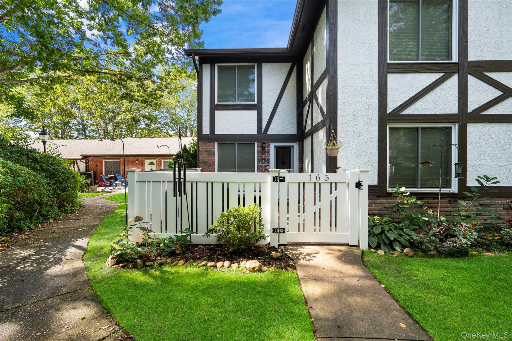 Front view of property featuring stucco siding, brick siding, and a gate