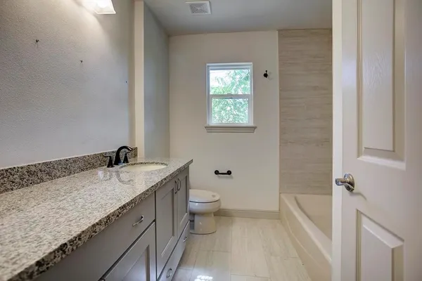 a bathroom with a granite countertop sink a toilet and shower
