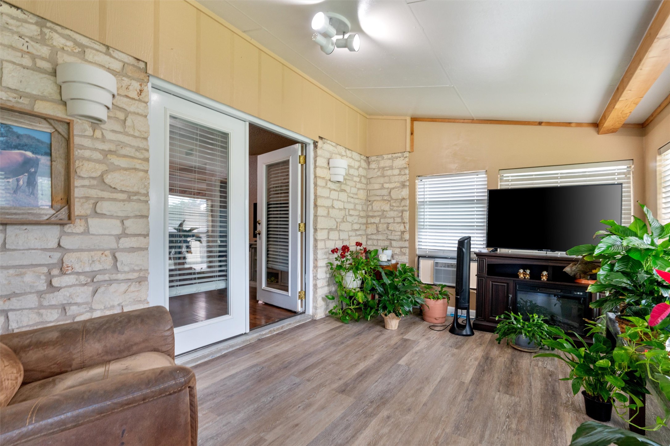 401 Drake Lane Taylor, TX 76574 - Photo 26 of 31 Enclosed living area featuring wood-finish flooring, stone accent walls, ceiling fan, and double French doors with blinds