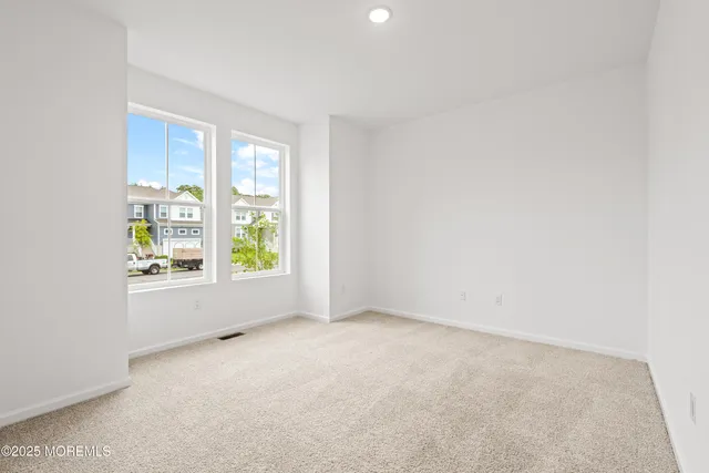 an empty room with wooden floor fireplace and windows
