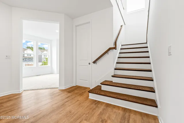a view of a hallway with stairs and wooden floor