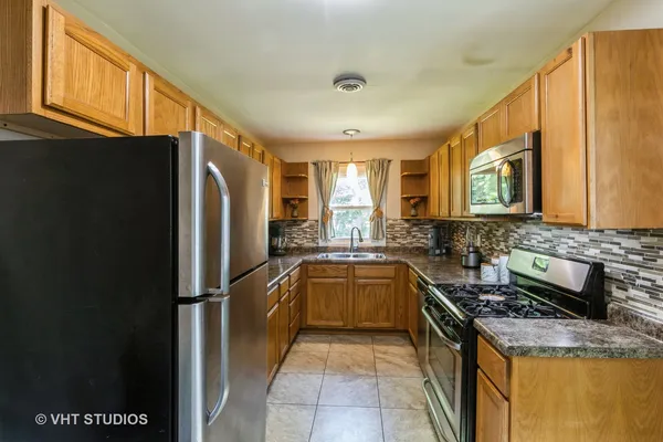 a kitchen with granite countertop a refrigerator stove and sink