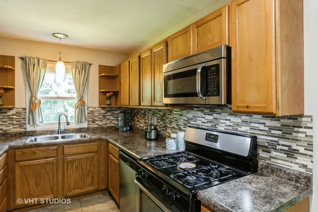a kitchen with stainless steel appliances granite countertop a stove a sink and a microwave