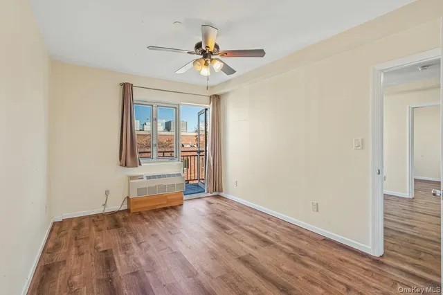 an empty room with wooden floor chandelier fan and windows