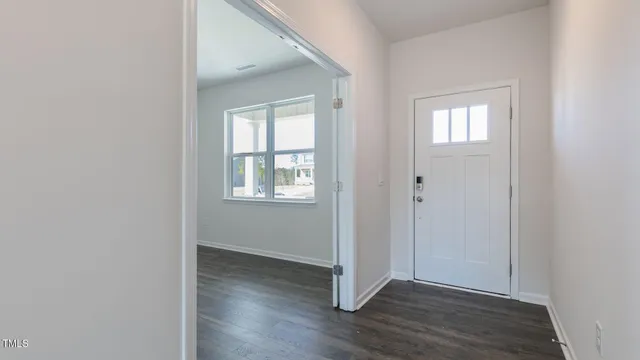 an empty room with wooden floor closet and windows