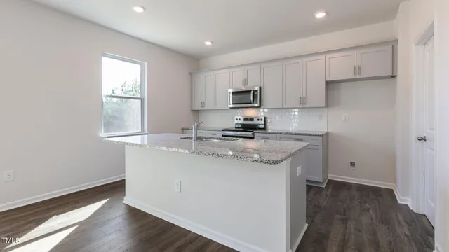 a kitchen with kitchen island granite countertop a sink cabinets and wooden floor