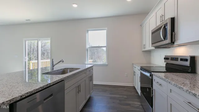 a kitchen with granite countertop a sink stainless steel appliances and cabinets