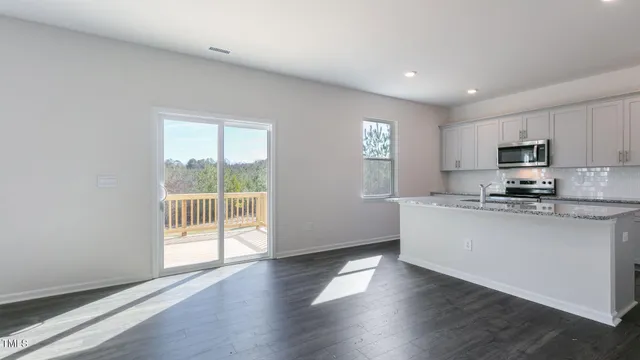 a large kitchen with hardwood floor a sink a window and appliances