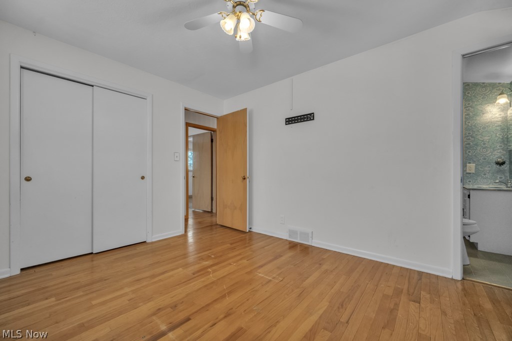 6846 Revere Road Cleveland, OH 44130 - Photo 23 of 30 Unfurnished bedroom with light wood-style flooring, a closet, a ceiling fan, and connected bathroom