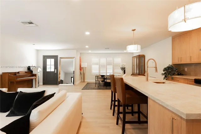 a large white kitchen with a stove a sink a refrigerator and a dining table with wooden floor