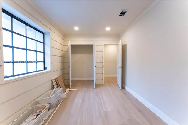 a view of empty room with wooden floor and fan