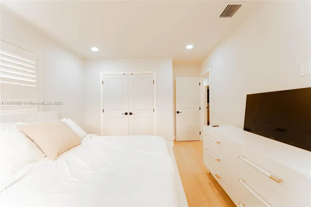 a spacious bedroom with a bed and a flat screen tv