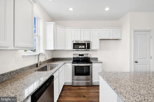 a kitchen with granite countertop white cabinets and stainless steel appliances