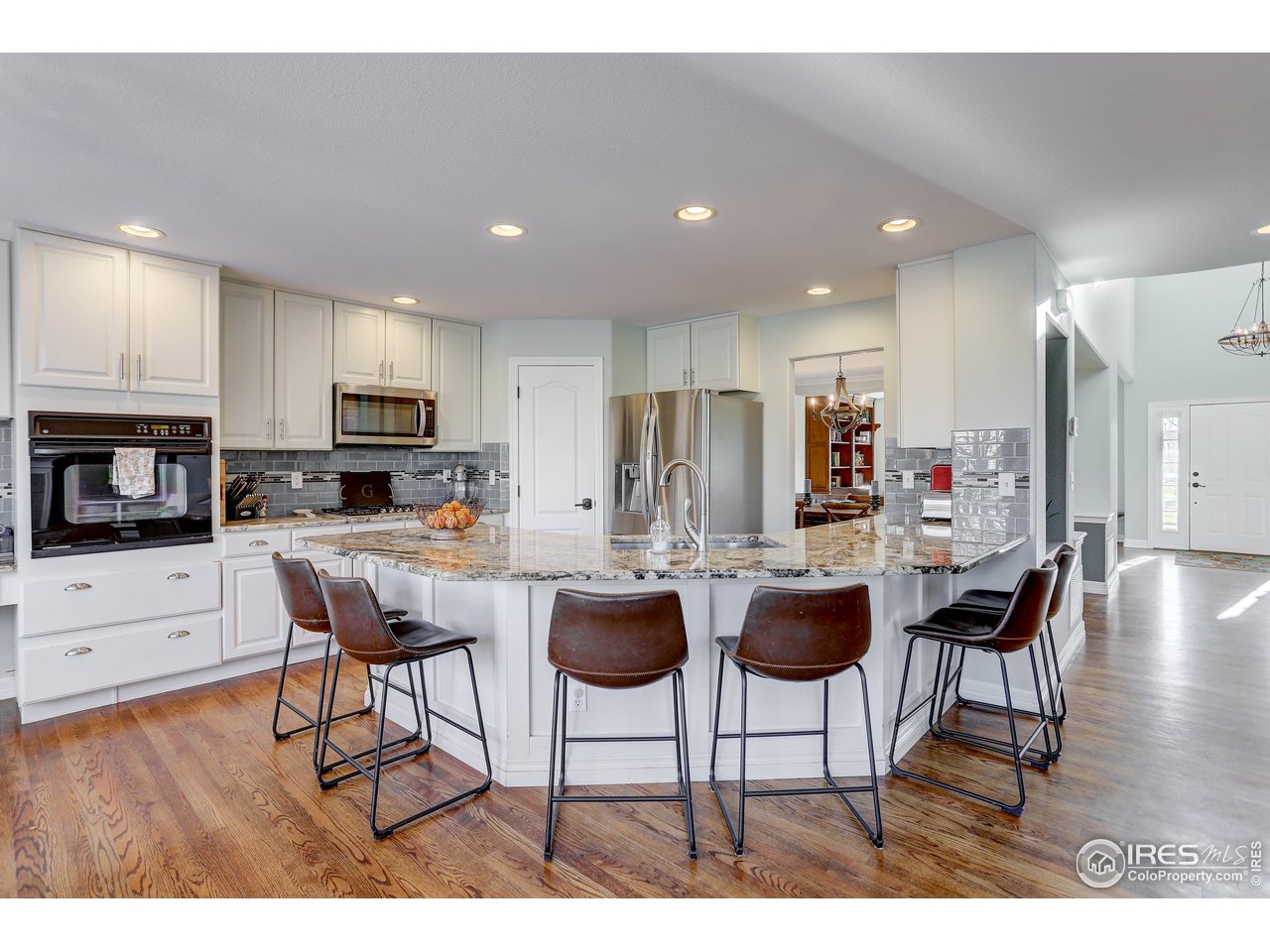 11744 Riverview Road Longmont, CO 80504 - Photo 22 of 40 a kitchen with stainless steel appliances kitchen island granite countertop a dining table chairs and a refrigerator