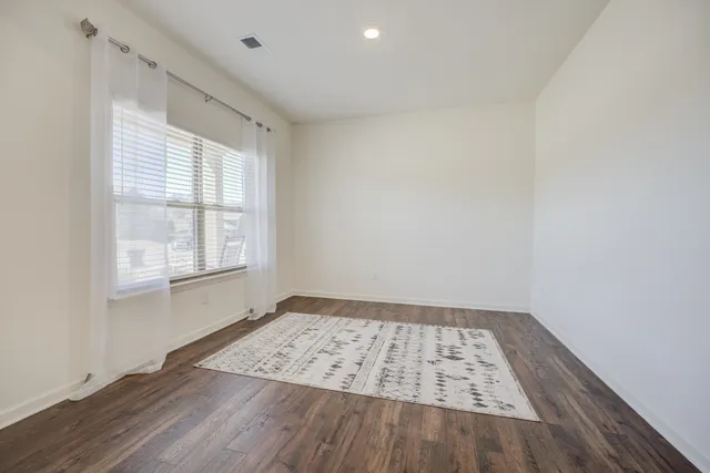 an empty room with wooden floor a exposed radiator and a window