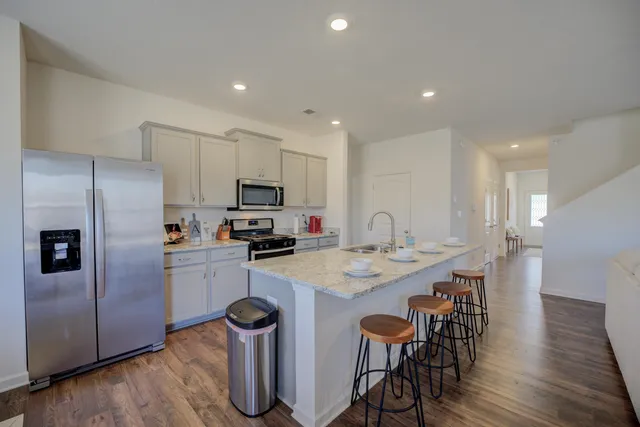 a kitchen with stainless steel appliances kitchen island granite countertop a table chairs microwave and refrigerator