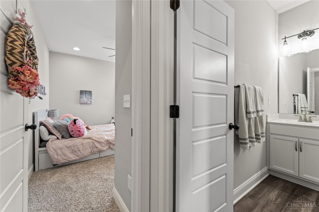 2425 Middleboro Road Clarksville, OH 45113 - Photo 79 of 91 This interior image showcases a bedroom with soft carpeting and an adjacent bathroom with wood flooring.