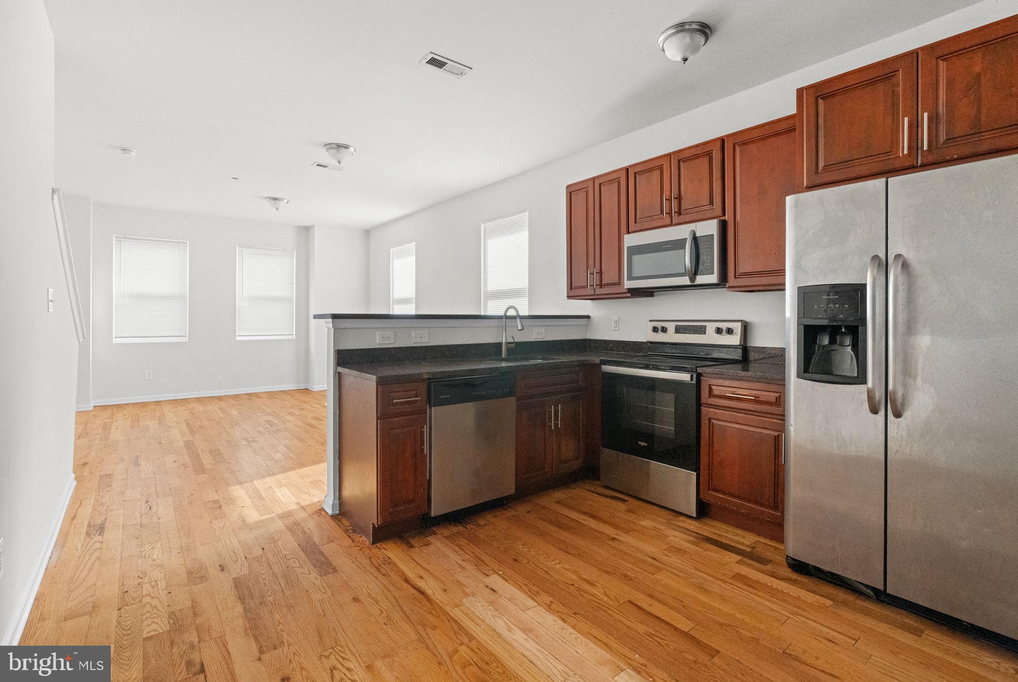 2106 North 17th Street Philadelphia, PA 19121 - Photo 47 of 84 a kitchen with stainless steel appliances granite countertop a stove a sink dishwasher a refrigerator and a microwave oven with wooden floor