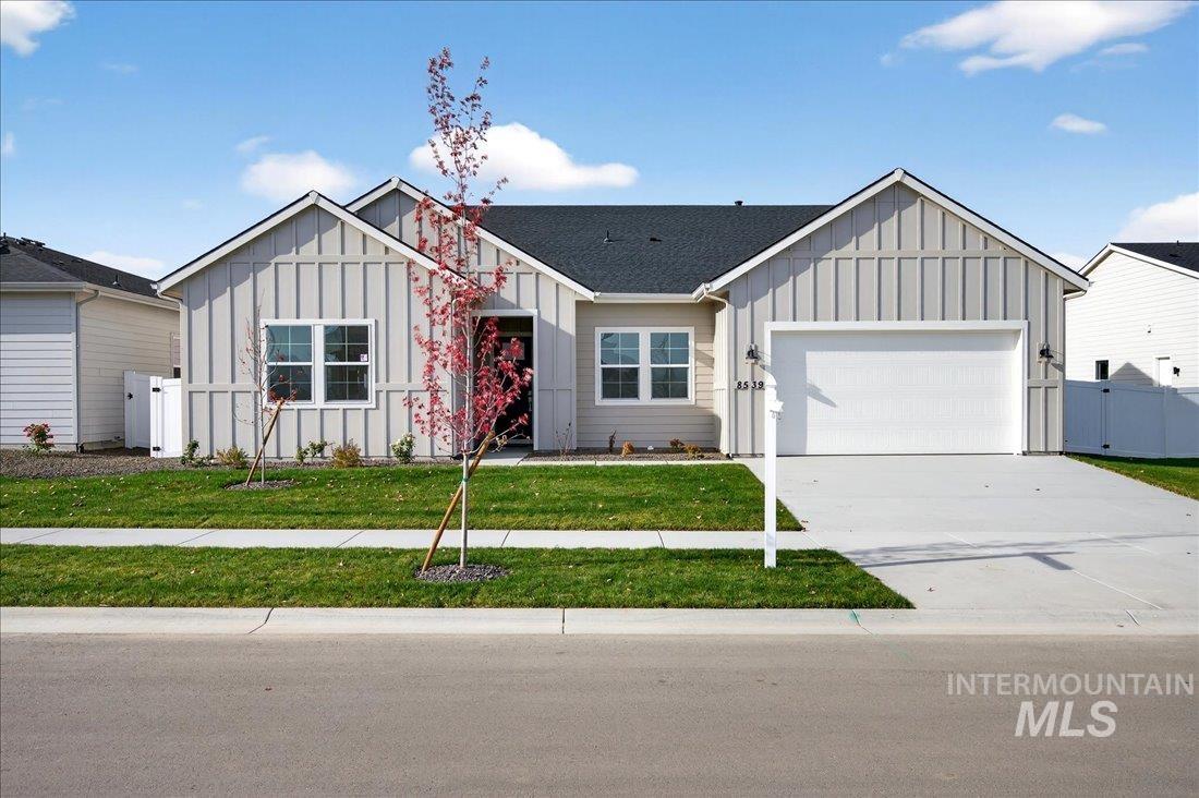 View of front of property featuring board and batten siding, driveway, a garage, and a gate