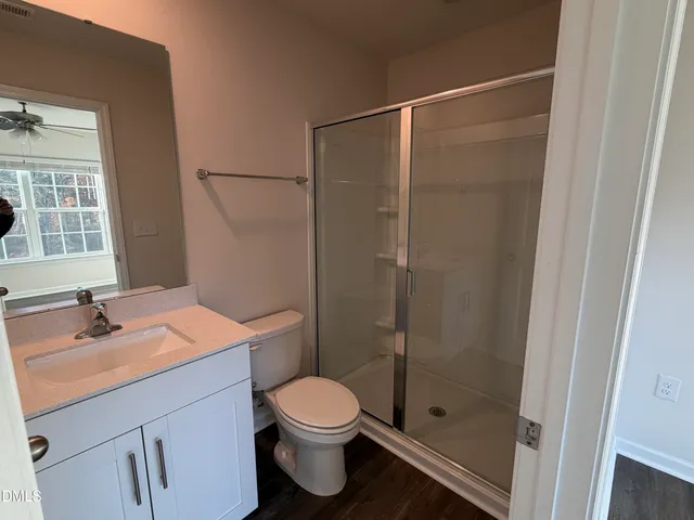 a bathroom with a shower sink vanity mirror and toilet
