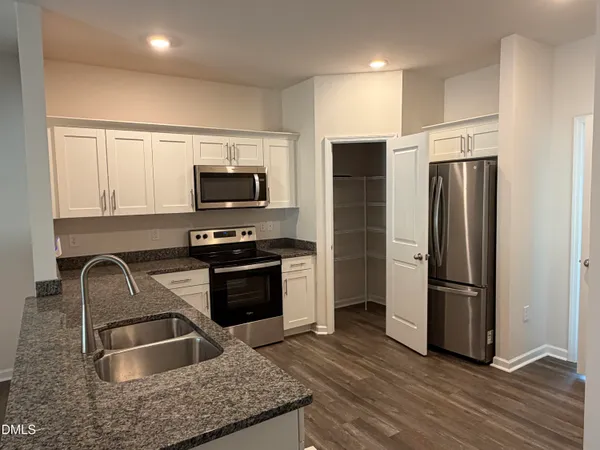 a kitchen with granite countertop a refrigerator and a sink