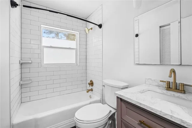 a bathroom with a granite countertop toilet a sink and a bathtub