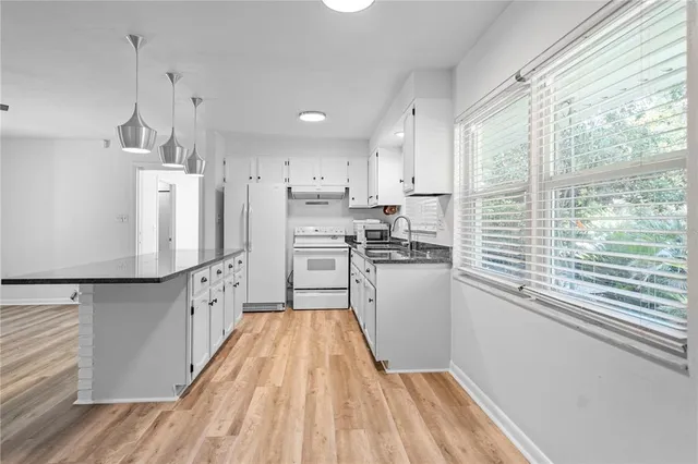 a kitchen with white cabinets and wooden floor