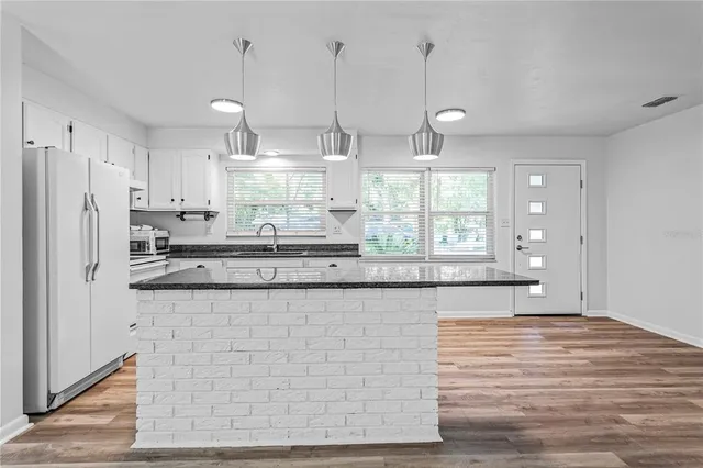 a kitchen with stainless steel appliances granite countertop a sink a stove a refrigerator a center island and cabinets