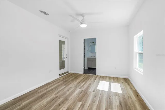 an empty room with wooden floor cabinet and windows