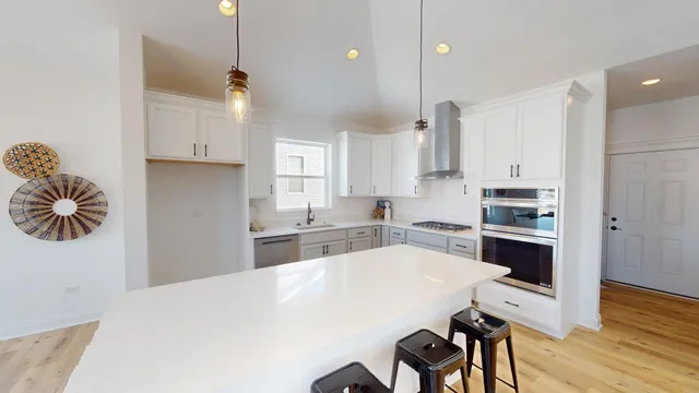 a kitchen with stainless steel appliances kitchen island granite countertop a stove a sink a refrigerator and white cabinets with wooden floor